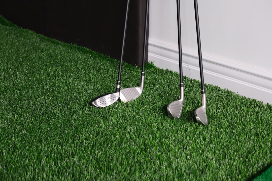 Four golf clubs stand upright on green artificial turf.
