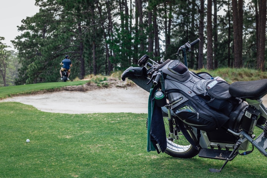 Golf clubs mounted on a scooter on a green course.