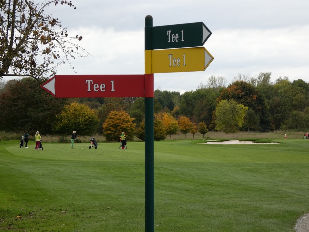Golfers practice on a course with an autumn signpost.
